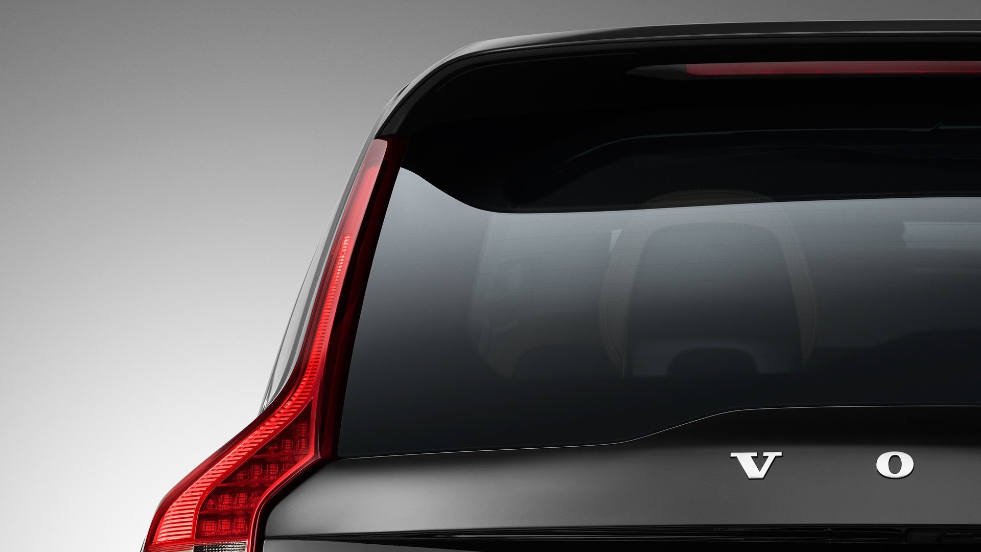 Primer plano de la luneta trasera y la luz trasera de un vehículo Volvo, mostrando parte del logotipo de Volvo.