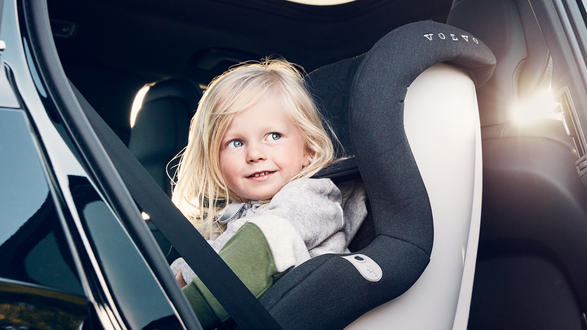 A child seated in a Volvo-branded car seat in the back seat of a vehicle, highlighting Volvo's focus on child safety.