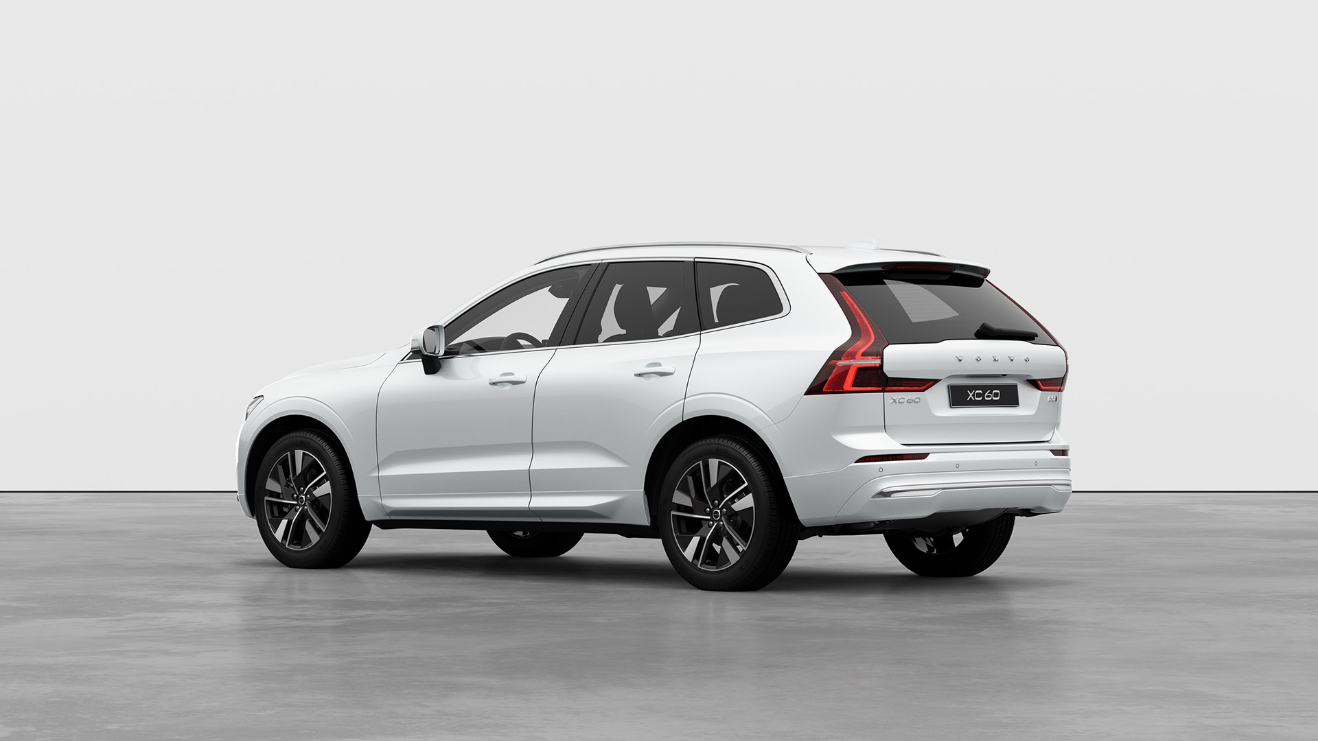 صورة خلفية وجانبية لسيارة فولفو XC60 الرياضية متعددة الاستخدامات بيضاء في استوديو بسيط.