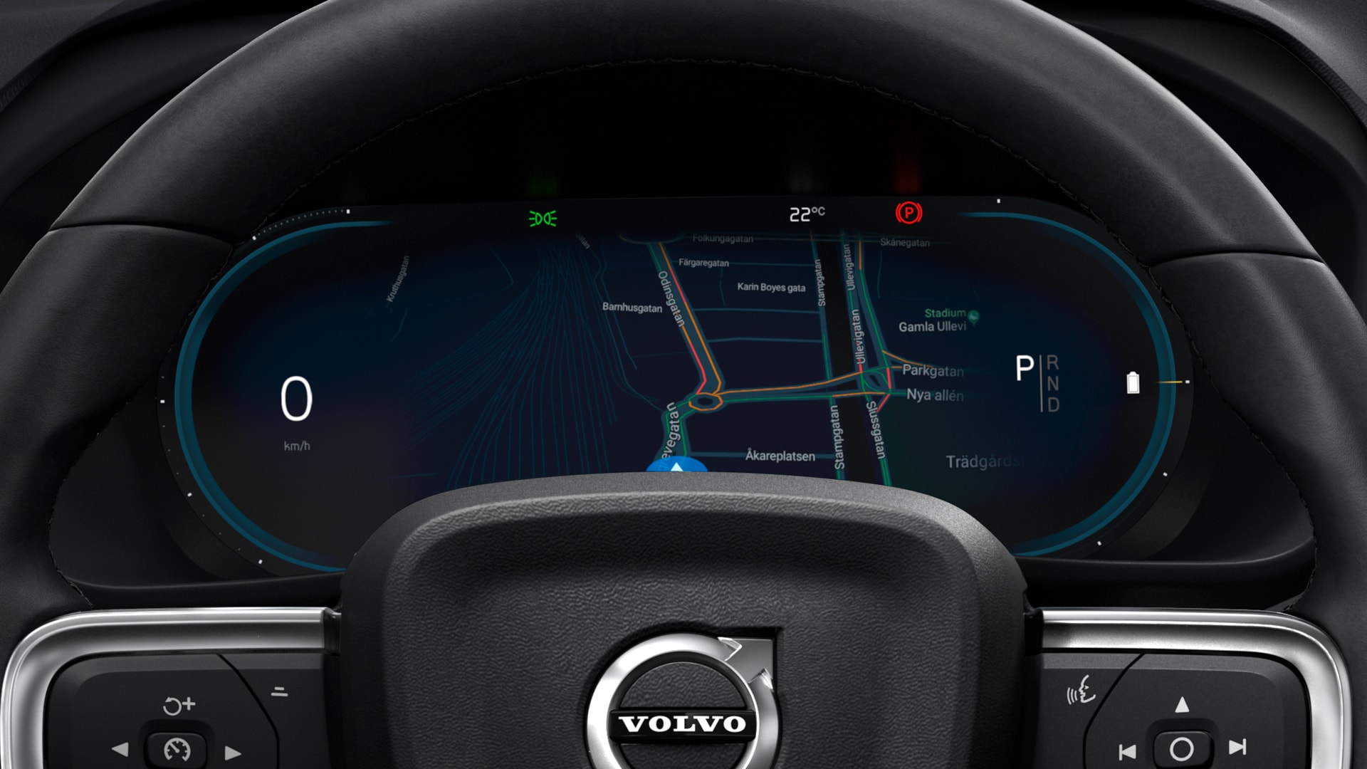 Afișajul digital pentru șofer al unei mașini Volvo, care arată direcțiile de navigație, vitezometrul la 0 km/h, poziția treptelor de viteză și sigla Volvo pe volan.